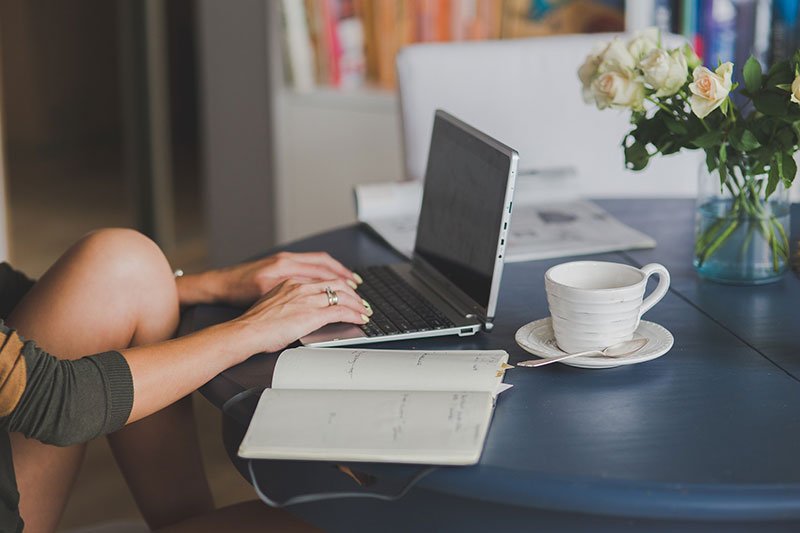 woman sitting at her desk. computer open and a coffee cup to the side